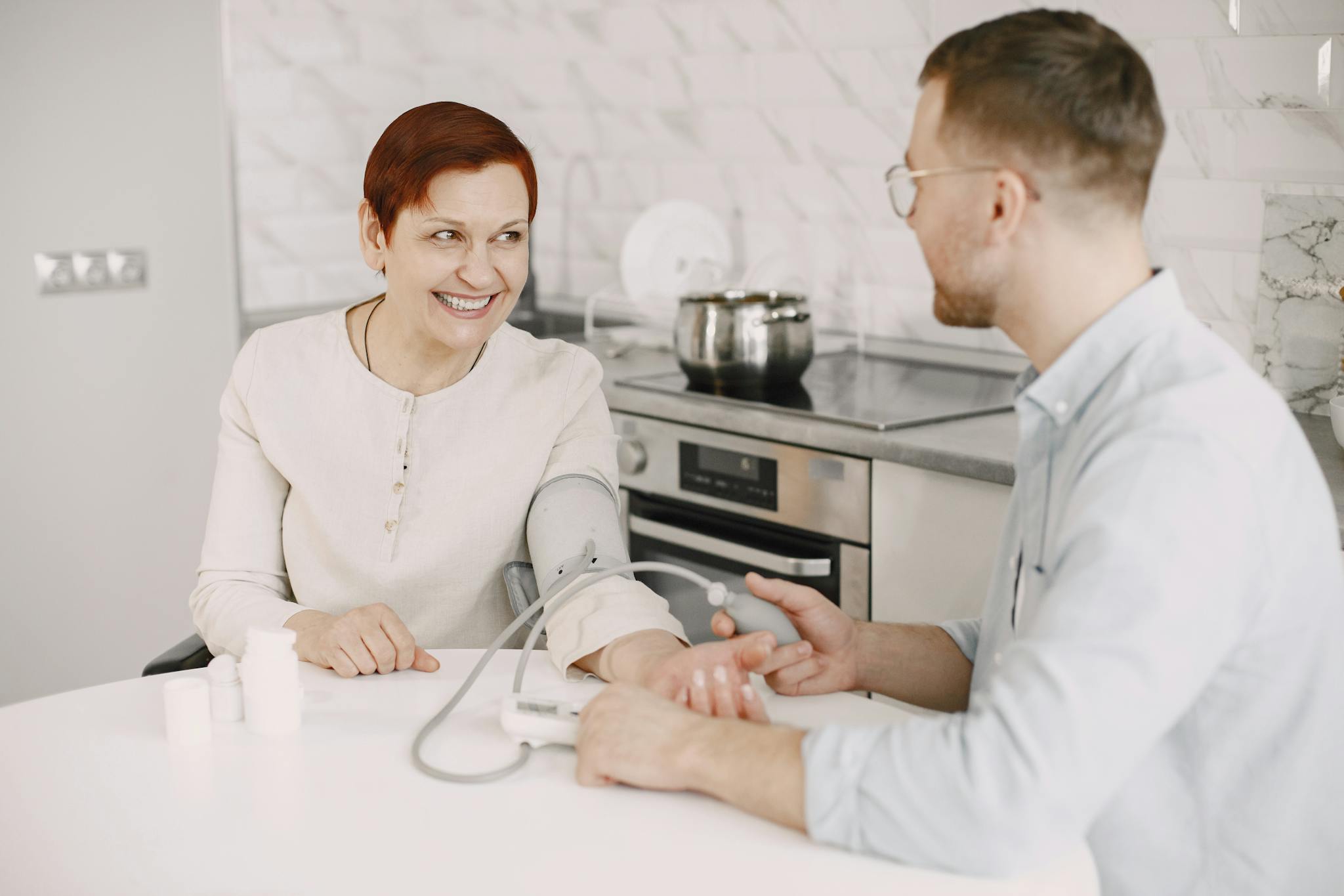 A healthcare professional checks a patient's blood pressure indoors, showcasing a friendly and caring interaction.